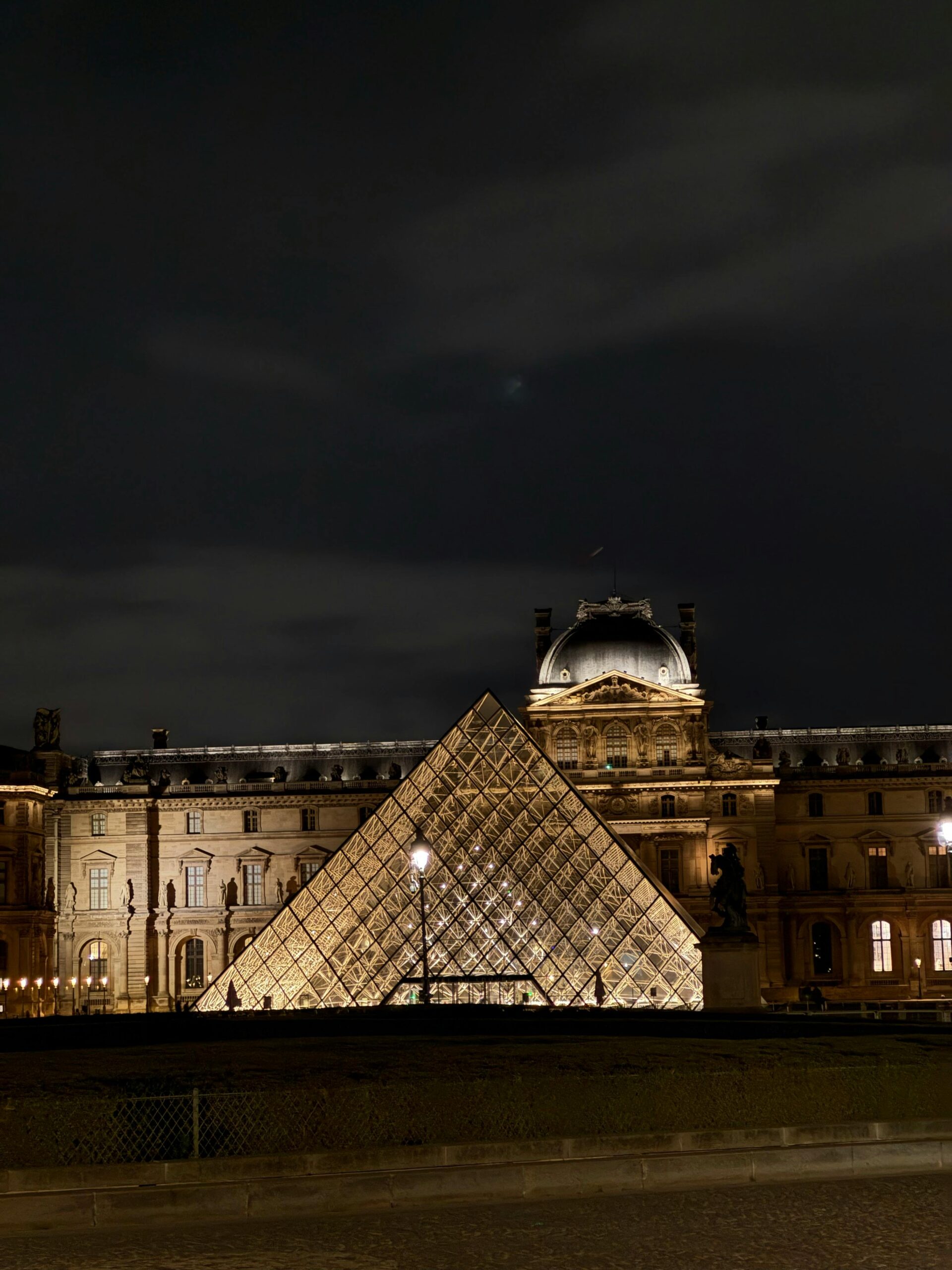 Stunning view of the Louvre Pyramid glowing against the night sky in Paris, France.